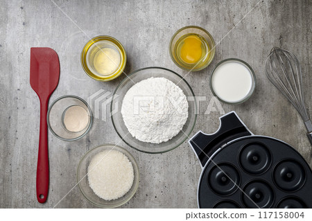 A kitchen counter with a variety of ingredients and utensils for making donuts A kitchen counter with a variety of ingredients and utensils for making donuts 117158004