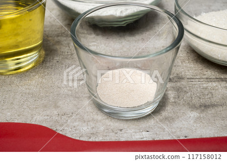 A glass bowl with a yeast in it sits on a table next to other bowls A glass bowl with a yeast in it sits on a table next to other bowls 117158012