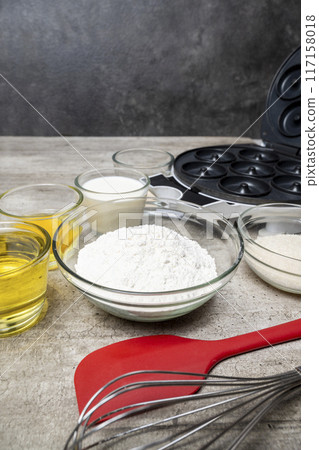 A table with several bowls of ingredients, including flour, sugar, and oil 117158018