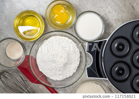 A red and silver whisk is on a table with other kitchen items 117158021