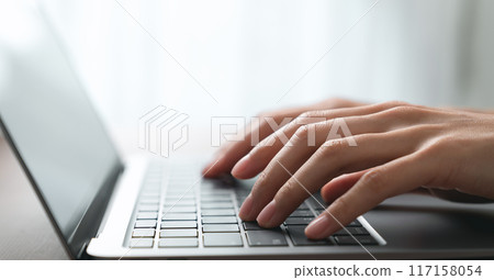 Hand using computer laptop and touching mouse on the table. 117158054