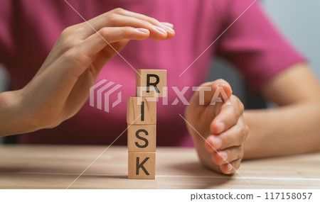 Hand preventing falling wooden blocks with risk word. Hand preventing falling wooden blocks with risk word. 117158057