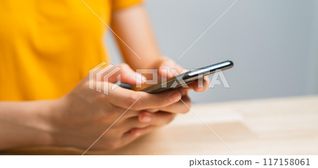 Hand holding smartphone with using social media on internet on table. 117158061