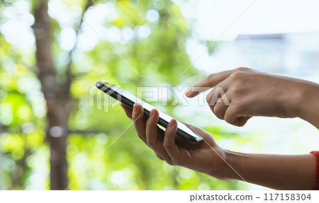 Hand holding smartphone with using social media on internet on table. Hand holding smartphone with using social media on internet on table. 117158304