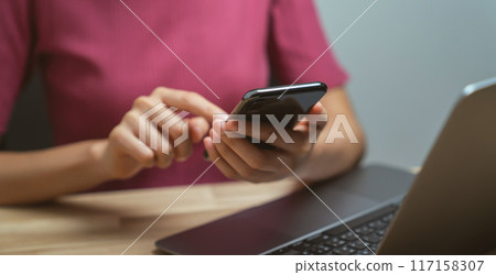 Hand holding smartphone with using social media on internet on table. Hand holding smartphone with using social media on internet on table. 117158307