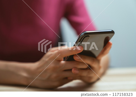 Hand holding smartphone with using social media on internet on table. 117158323