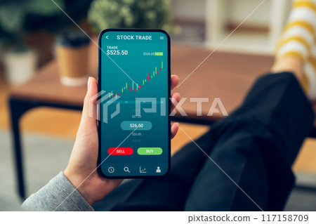 Businessman trader using smartphone with stock market investments and graph on screen to analyze trading data, buy or sell and checking price on mobile application. Businessman trader using smartphone with stock market investments and graph on screen to analyze trading data, buy or sell and checking price on mobile application. 117158709