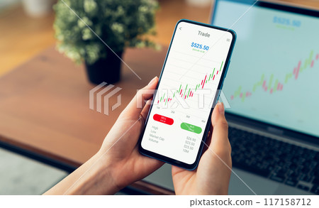 Businessman trader using smartphone with stock market investments and graph on screen to analyze trading data, buy or sell and checking price on mobile application. Businessman trader using smartphone with stock market investments and graph on screen to analyze trading data, buy or sell and checking price on mobile application. 117158712