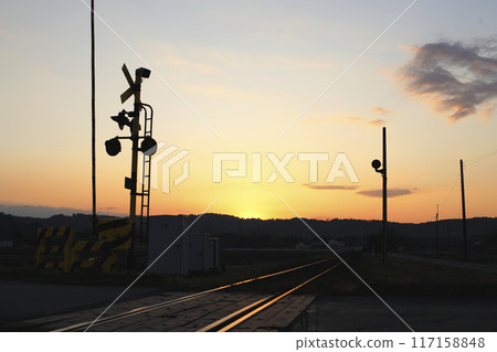 Railroad tracks and alarms shining in the setting sun Silhouette of a small hill Railroad tracks and alarms shining in the setting sun Silhouette of a small hill 117158848