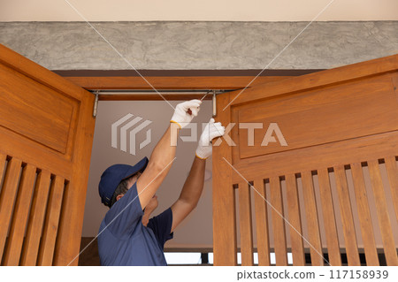 Handyman fixing bifold doors sticking or not sliding properly. 117158939