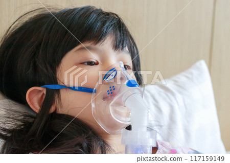 Sick little asian girl inhalation with nebulizer for respiratory treatment 117159149