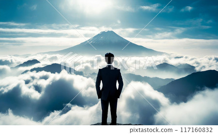 設定高目標的形象。一位商人站在山頂,望向更高的山的後側輪廓。 設定高目標的形象。一位商人站在山頂,望向更高的山的後側輪廓。 117160832