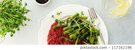 Beetroot risotto with rice and sesame seeds, baked asparagus with microgreens 117162196