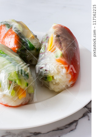 These traditional Vietnamese spring rolls feature rice paper filled with lettuce, salmon, carrots, and cucumber, served with fish sauce, offering a light and flavorful appetizer These traditional Vietnamese spring rolls feature rice paper filled with lettuce, salmon, carrots, and cucumber, served with fish sauce, offering a light and flavorful appetizer 117162215