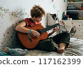 girl playing guitar in home 117162399