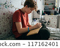 Teenage girl doing homework while sitting in the room.	 117162401