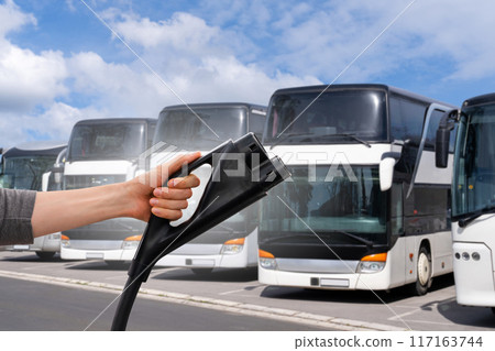 Hand with electric plug on a background of buses 117163744