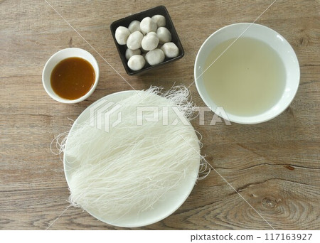 dry instant vermicelli thin noodles raw food on plate with steamed pork ball dipping spicy and sour chili sauce couple soup prepare to cook dry instant vermicelli thin noodles raw food on plate with steamed pork ball dipping spicy and sour chili sauce couple soup prepare to cook 117163927