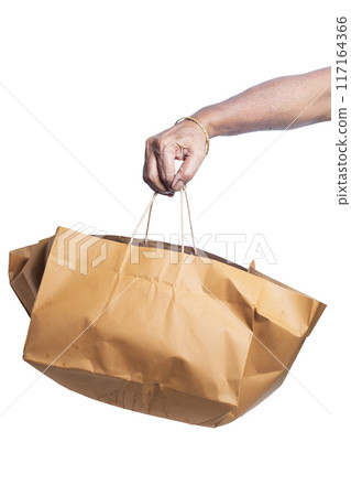 Hand holding shopping brown paper bag isolated on white background with clipping path. Closeup Hand holding shopping brown paper bag isolated on white background with clipping path. Closeup 117164366