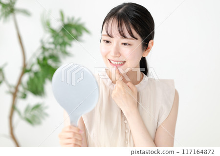 一個女人用手鏡檢查她的牙齒 117164872