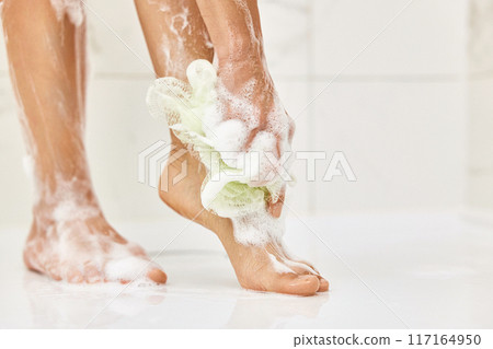 Woman washing her legs with foam bubbles and bath sponge while taking shower in the bathroom Woman washing her legs with foam bubbles and bath sponge while taking shower in the bathroom 117164950