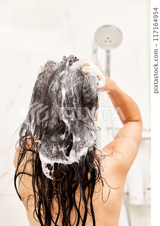Young woman taking refreshing shower in modern bathroom. Girl washing her hair, back view. Rinsing it out 117164954
