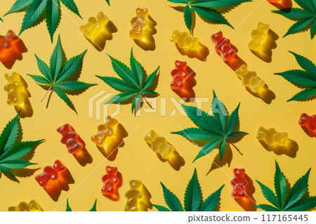 Colorful Gummy Bears with Cannabis Leaves on Bright Yellow Background 117165445