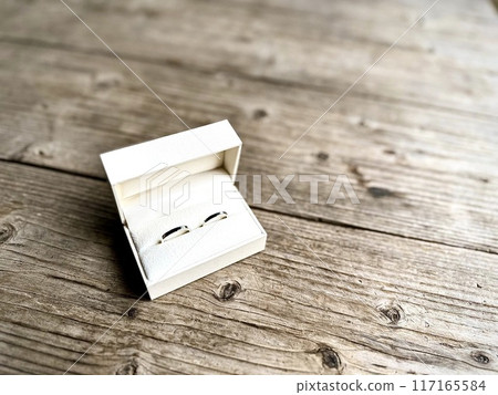 Wedding rings in a gift box on a wooden desk 117165584