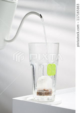 A Pristine Tea Bag Awaits Infusion In Clear Glass. 117165863