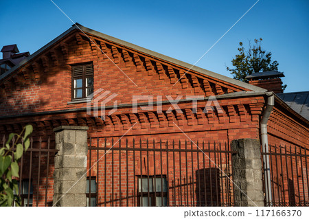 An old, renovated, brick house, behind a fence 117166370