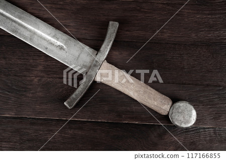 Medieval sword on wooden background. 117166855