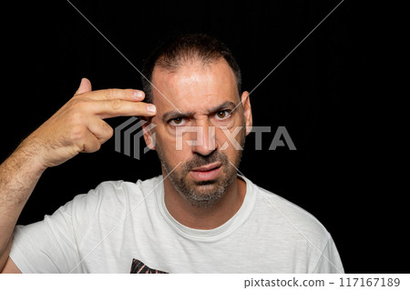 Bearded hispanic man around 40 years old isolated over dark background making gun gesture with his hand pointing to his head. Bearded hispanic man around 40 years old isolated over dark background making gun gesture with his hand pointing to his head. 117167189