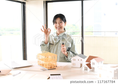 穿著工作服的女人在房屋模型前拿著放大鏡 117167784