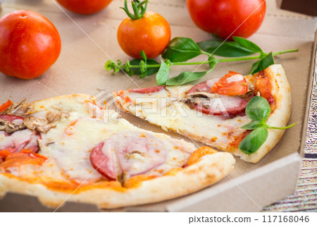 cooked pizza with salami and sausage in a box on a wooden table 117168046