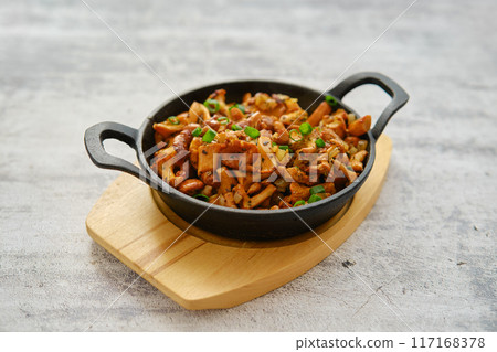 Wild chanterelle mushrooms roasted with thyme and onion in a frying pan 117168378