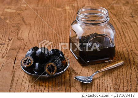 Saucer and jar with preserved walnuts on wooden background Saucer and jar with preserved walnuts on wooden background 117168412