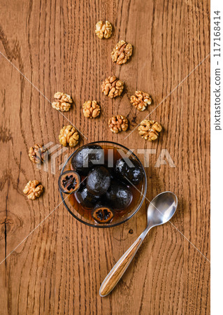 Overhead view of saucer with homemade preserved walnut jam and walnut kernels 117168414