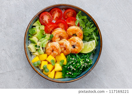 Poke bowl with shrimp, avocado, radish, carrot, tomato, chuka seaweed and white rice. Soy sauce, lime and sesame dressing. Green table background, top view Poke bowl with shrimp, avocado, radish, carrot, tomato, chuka seaweed and white rice. Soy sauce, lime and sesame dressing. Green table background, top view 117169221