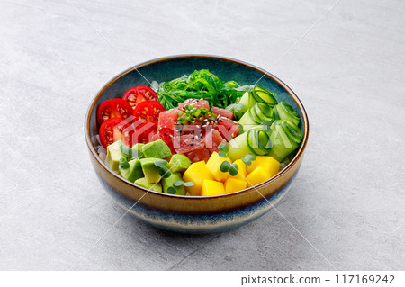 Healthy tuna poke bowl overhead top view. Poke is a traditional Hawaiian dish influenced by japanese and asian cuisine. Ahi poke is made of raw tuna chunks tossed over rice and topped with vegetables. Healthy tuna poke bowl overhead top view. Poke is a traditional Hawaiian dish influenced by japanese and asian cuisine. Ahi poke is made of raw tuna chunks tossed over rice and topped with vegetables. 117169242
