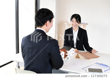 年輕男女辦公室職員使用房屋模型召開會議 年輕男女辦公室職員使用房屋模型召開會議 117169275