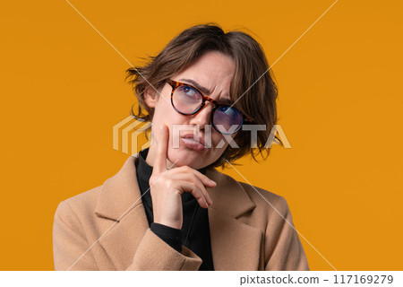 Thinking around businesswoman on yellow background. Puzzled lady looking answer Thinking around businesswoman on yellow background. Puzzled lady looking answer 117169279