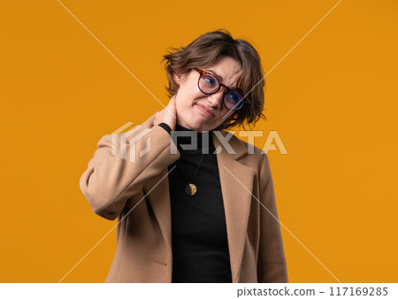 Tired young businesswoman feeling pain in neck joint, massaging muscles, rubbing head. Lady with discomfort because of arthritis. Health care, medical concept Tired young businesswoman feeling pain in neck joint, massaging muscles, rubbing head. Lady with discomfort because of arthritis. Health care, medical concept 117169285