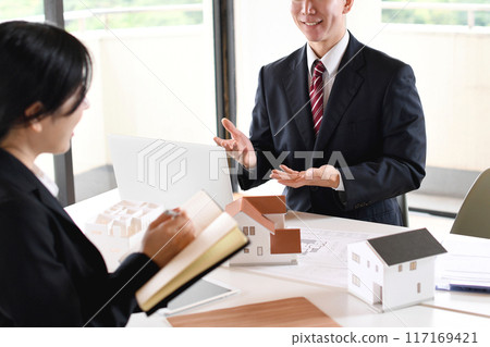 年輕男女辦公室職員使用房屋模型召開會議 117169421