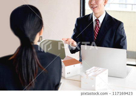 Young male and female office workers having a meeting using a house model 117169423