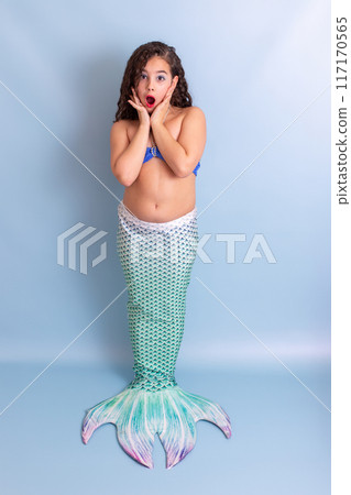 Cute surprised girl in mermaid costume stand on blue background 117170565