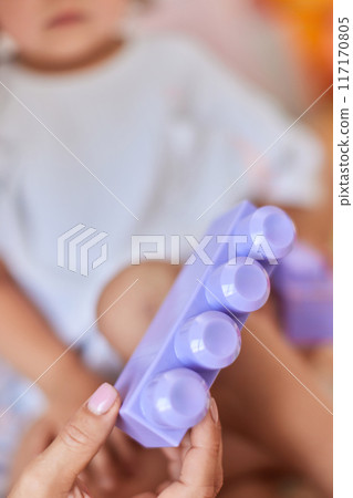 mom showing her little child girl purple plastic building toy block 117170805
