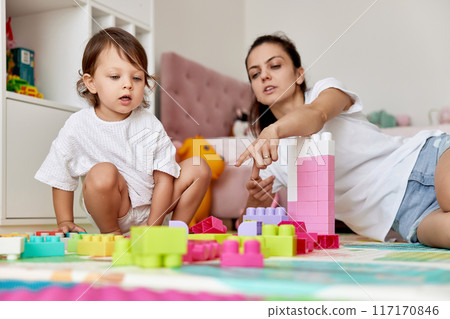 cute baby girl and her loving mother playing with toy bricks in the children room, early development 117170846