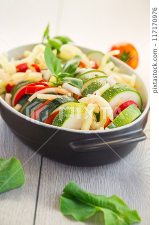 raw zucchini and tomatoes sliced and prepared for baking in a ceramic dish, vegetable appetizer raw zucchini and tomatoes sliced and prepared for baking in a ceramic dish, vegetable appetizer 117170976