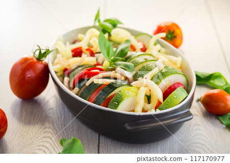 raw zucchini and tomatoes sliced and prepared for baking in a ceramic dish, vegetable appetizer raw zucchini and tomatoes sliced and prepared for baking in a ceramic dish, vegetable appetizer 117170977