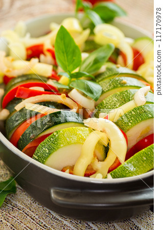 raw zucchini and tomatoes sliced and prepared for baking in a ceramic dish, vegetable appetizer raw zucchini and tomatoes sliced and prepared for baking in a ceramic dish, vegetable appetizer 117170978